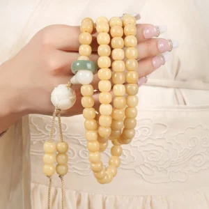 Multi-wrap bodhi seed mala bracelet held in hands showing jade spacer and white lotus charm