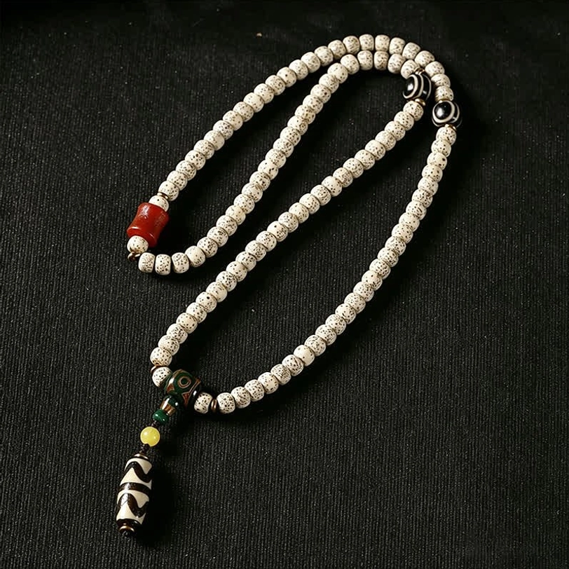 Coiled Tibetan 108 prayer mala with light grey bodhi beads, red agate decorative bead, and detailed Dzi pendant with green-yellow accents