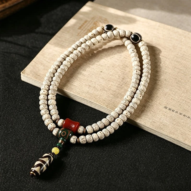 Handcrafted Tibetan Bodhi seed mala bracelet with black Dzi spacer beads and red agate accent on wooden surface