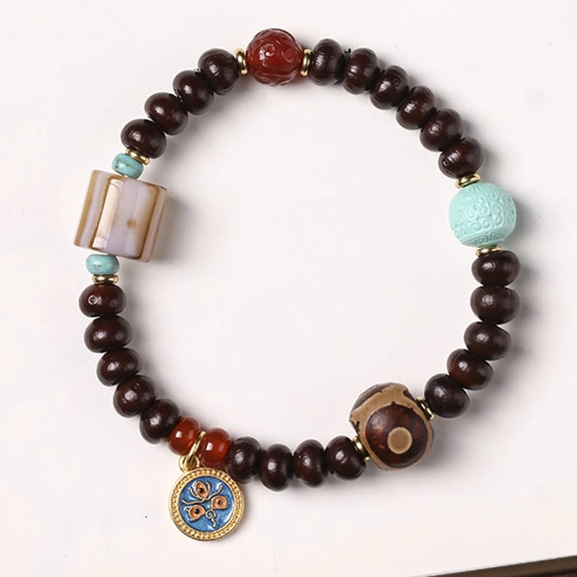 Handmade Tibetan bodhi seed bracelet featuring three-eye dzi amulet, purple wooden beads, red agate, turquoise, and enamel detail
