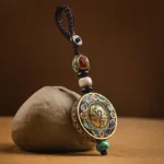 Tibetan Om Mani Padme Hum Bodhi seed keychain with brass pendant and turquoise tassel on stone background