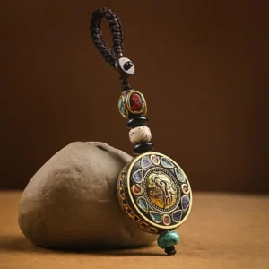 Tibetan Om Mani Padme Hum Bodhi seed keychain with brass pendant and turquoise tassel on stone background