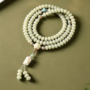 Tibetan white bodhi seed prayer beads mala with pale green beads and decorative spacer accents, top-down view