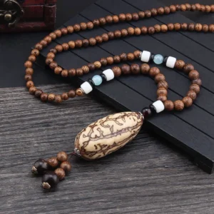 Tibetan bodhi seed necklace with large thousand-eyed pattern pendant and ethnic spacer beads on dark wood surface