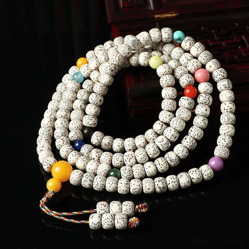 Colorful Tibetan bodhi seed prayer beads with mixed gemstone spacers and woven tassel on dark wood