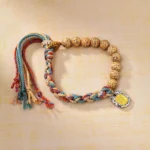 Tibetan multicolor bodhi seed bracelet with Zakiram goddess wealth charm and adjustable tassel, overhead flat lay view on neutral background
