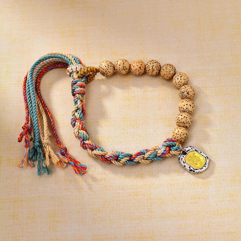 Tibetan multicolor bodhi seed bracelet with Zakiram goddess wealth charm and adjustable tassel, overhead flat lay view on neutral background