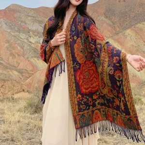 Bohemian tassel shawl draped over white long dress against mountain backdrop, front medium shot with paisley ethnic pattern visible