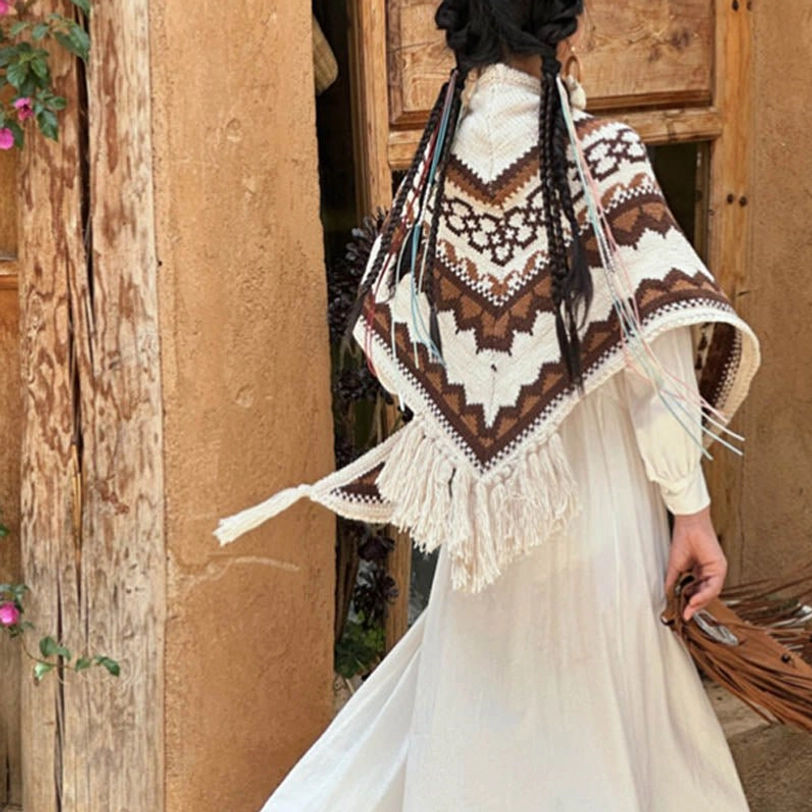 Brown and beige striped Tibetan shawl draped over back with long fringe trim, rear full-body view at adobe house entrance
