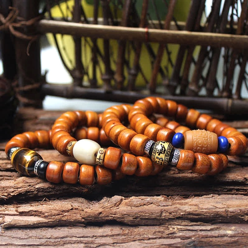 Multiple Tibetan bone bead bracelets with mixed gemstone spacers and metal charms on rustic wooden background