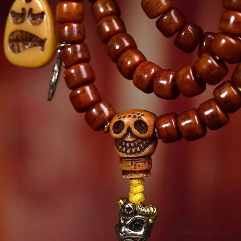 Front close-up view of Tibetan bone bead mala beads featuring reddish-brown beads with skull guru bead and angry face charm accent