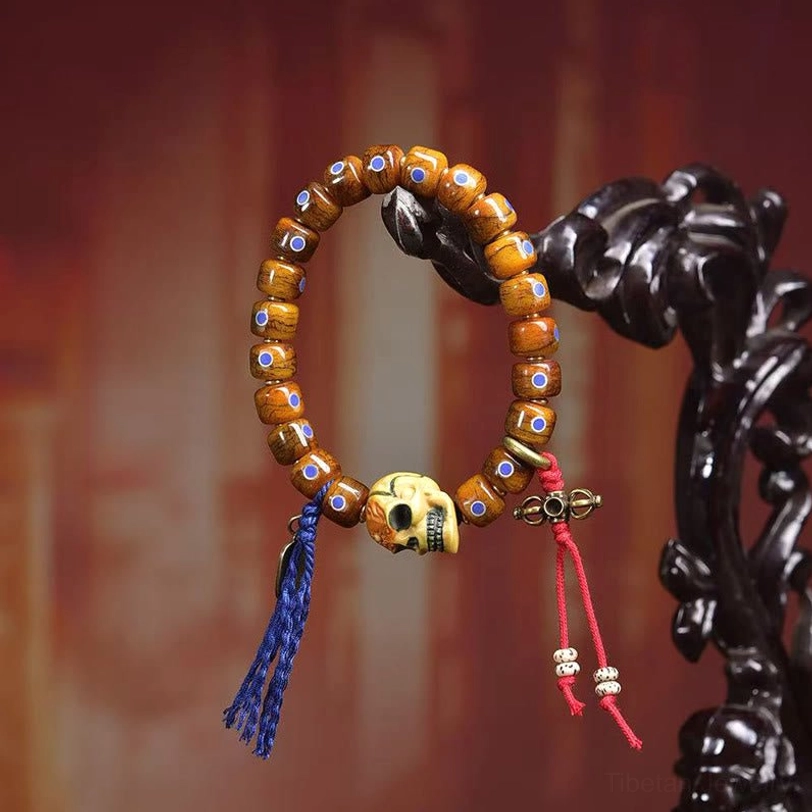 Tibetan bone skull bracelet featuring barrel beads and dual-colored tassels on carved wood background