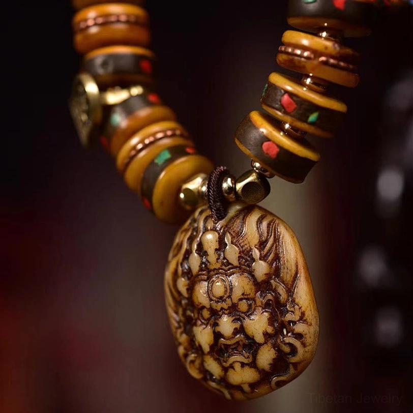Macro detail of Tibetan protection bracelet pendant showing carved folk deity face on camel bone with metal clasp and natural bead texture