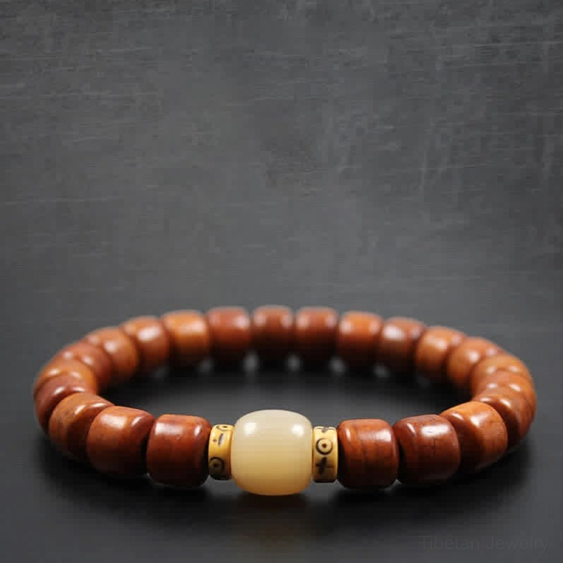 Tibetan bone bead bracelet with carved silver metal charm and red spacer beads on gray background