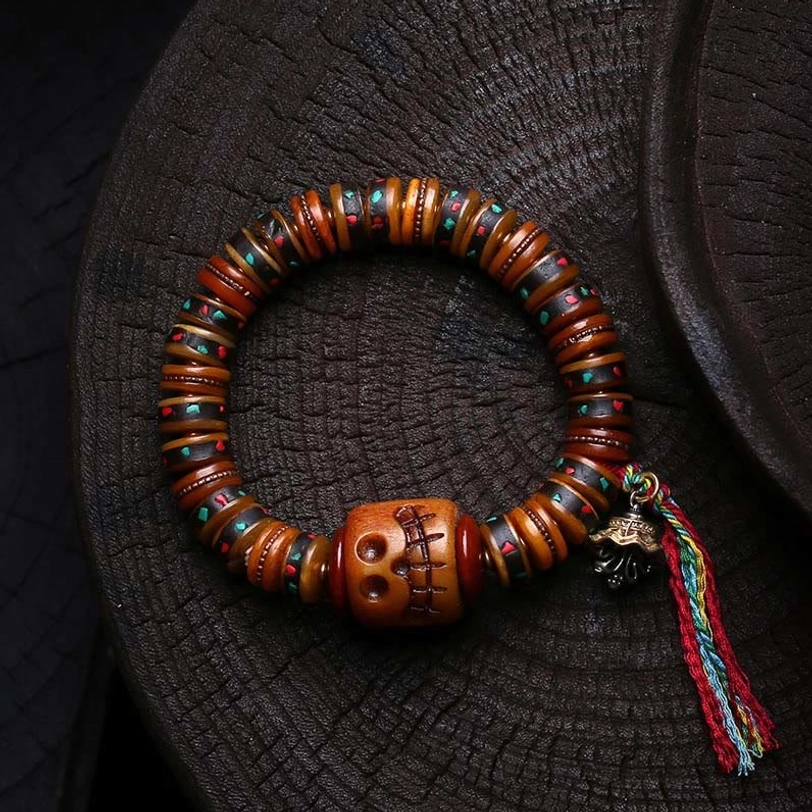 Handcrafted Tibetan bone bead bracelet featuring carved skull, colorful tassel accent, and brown bone beads