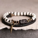 Tibetan bone ebony wood copper couple bracelet pair overhead view showing beaded design and bronze hardware on dark mat