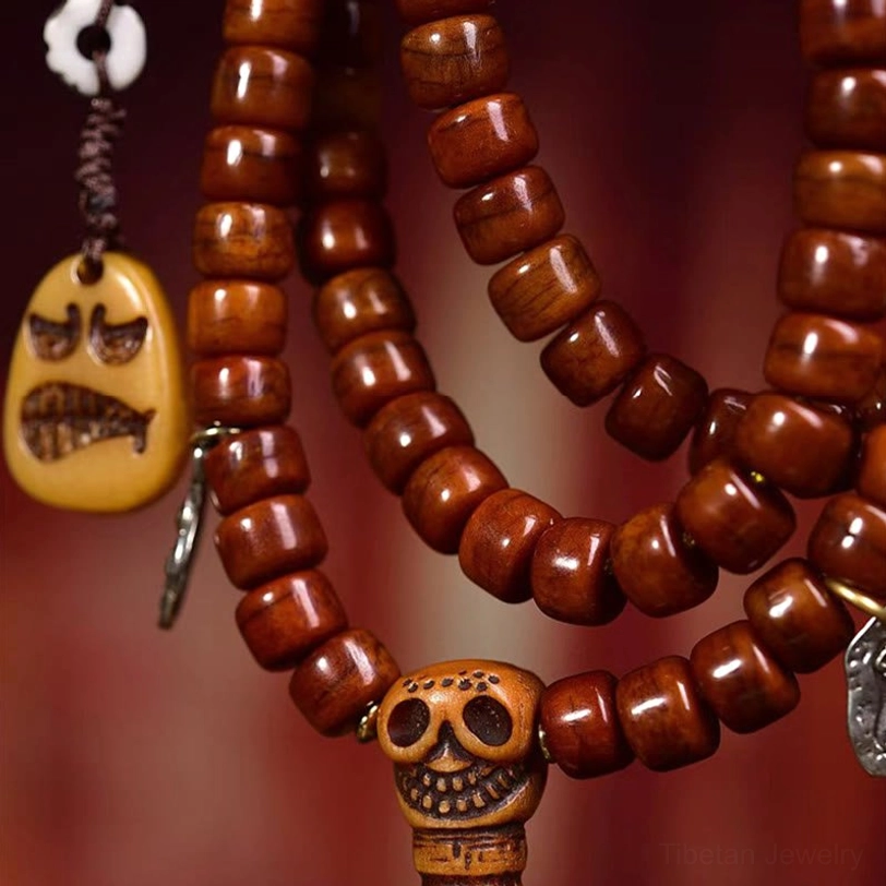 Detailed close-up of Tibetan bone bead mala front view showing barrel-shaped reddish-brown beads with angry face pendant and silver metal clips