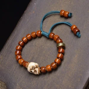 Reddish-brown bone skull bracelet with blue woven cord and metal spacer beads, adjustable fit