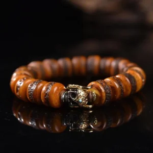 Tibetan bone skull bracelet with aged disc beads and metal skull charm, flat lay top view on dark reflective background
