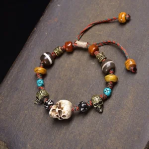 Tibetan bone skull beaded bracelet with multiple charms and adjustable elastic cord on dark wooden surface