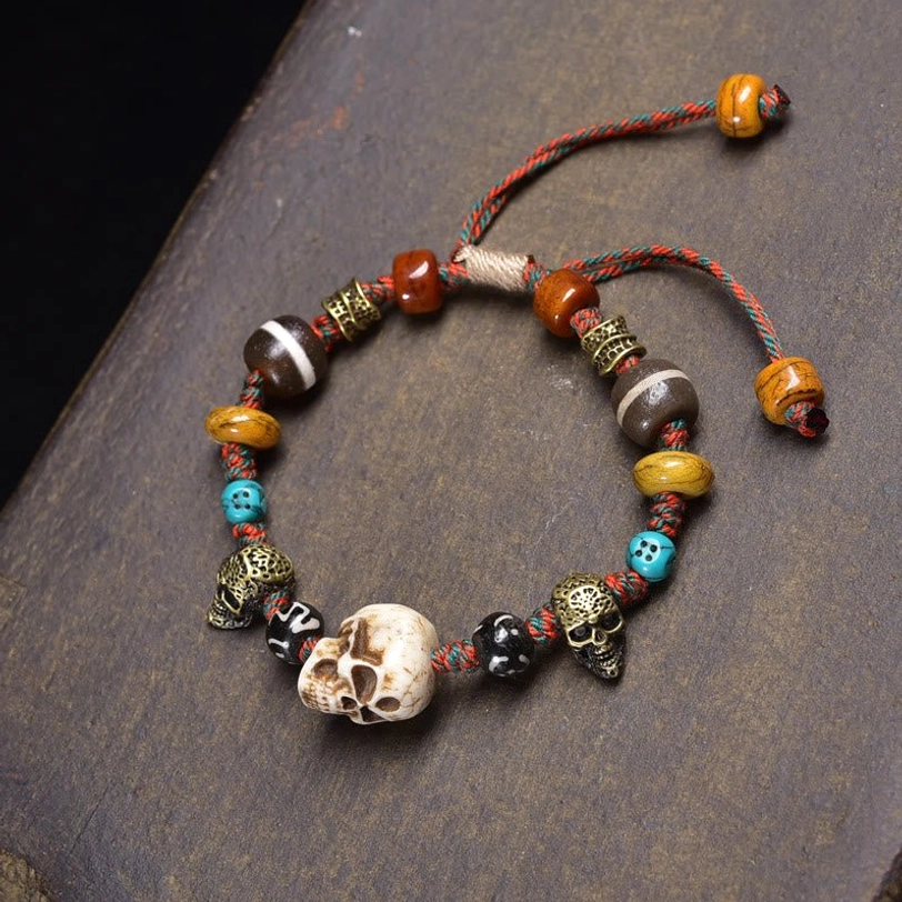 Tibetan bone skull beaded bracelet with multiple charms and adjustable elastic cord on dark wooden surface