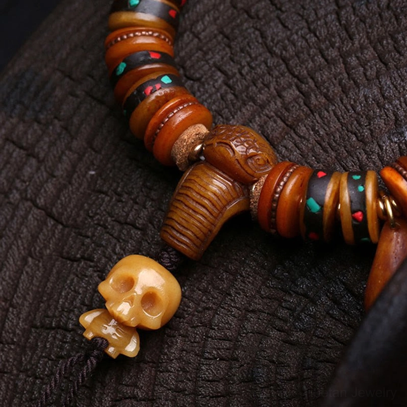 Close-up macro view of carved bone skull charm and colorful inlaid bead accents on Tibetan bracelet