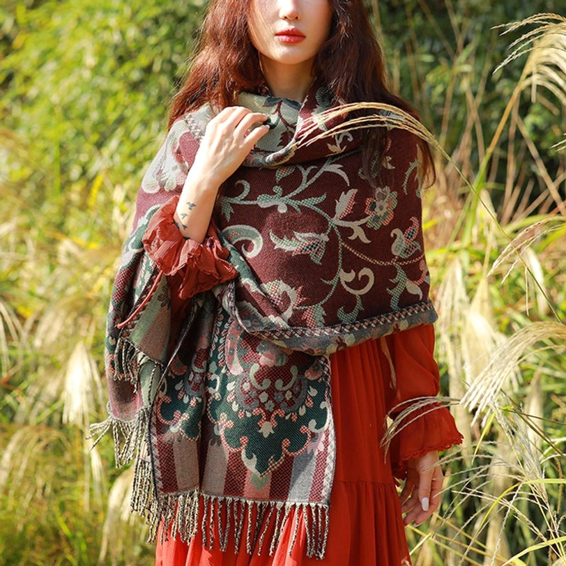 Tibetan botanical tassel shawl with dark red vine leaf pattern draped over shoulders in outdoor reed field setting