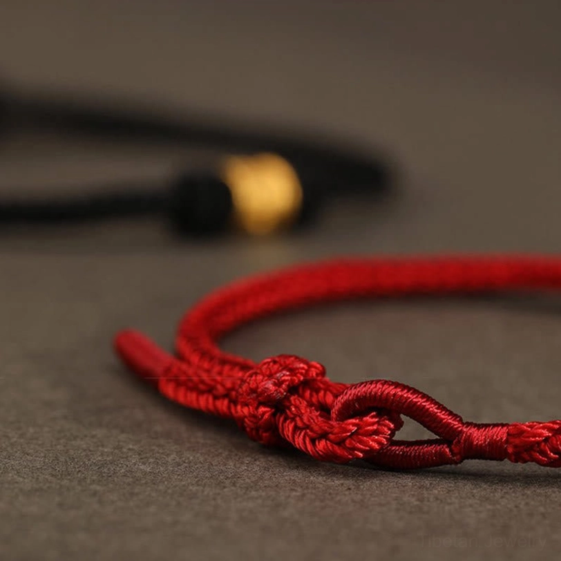 Handcrafted adjustable knot detail of Tibetan red string protection bracelet, artisan tying mechanism