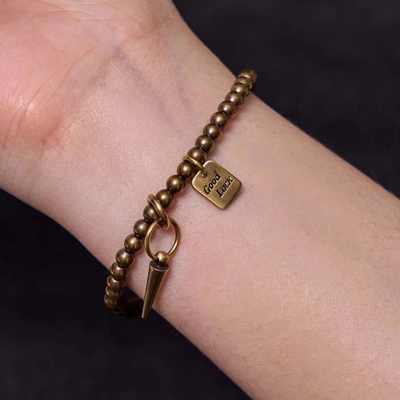 Side close-up view of prosperity bracelet on bare arm highlighting good luck charm and spike pendant
