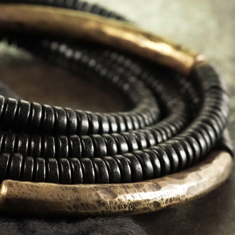 Detailed close-up view of ebony wood beads with hammered brass metal tubes, artisanal handmade bracelet components