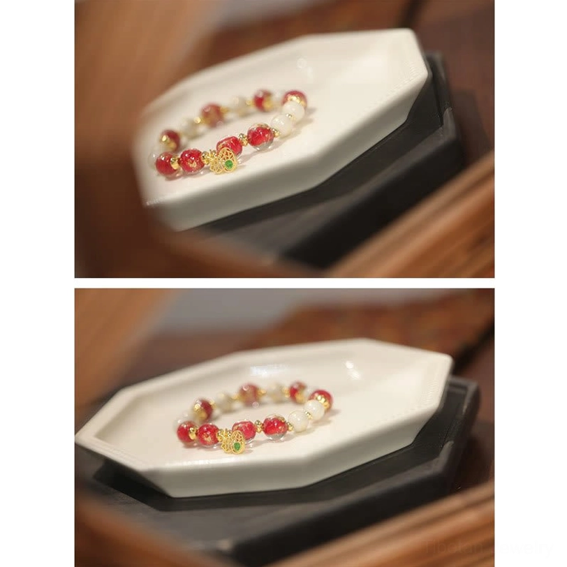 Micro close-up of Tibetan wealth bracelet displayed in miniature octagonal tray showing intricate red and gold bead craftsmanship