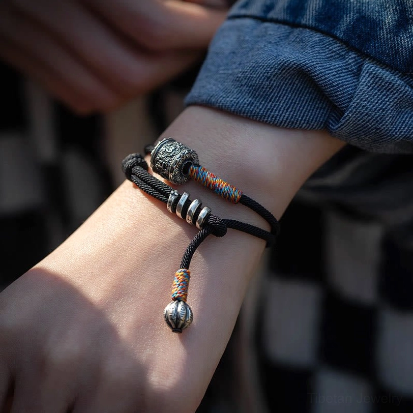Tibetan amulet bracelet bell pendant with double fish carving and woven thread wrap macro detail