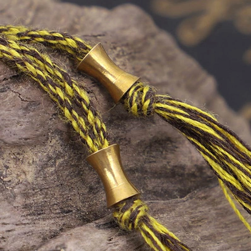 Tibetan mantra bracelet rope cord and brass metal fittings with decorative tassel on stone background