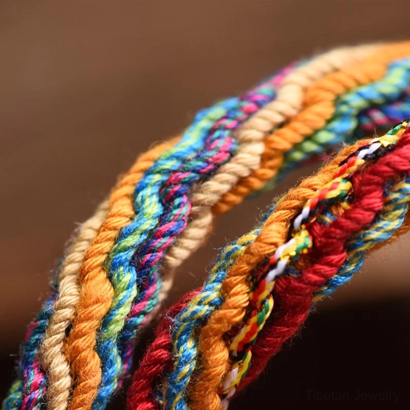 Macro view of Tibetan bracelet hand-braided multicolor cotton rope weave in red orange and blue
