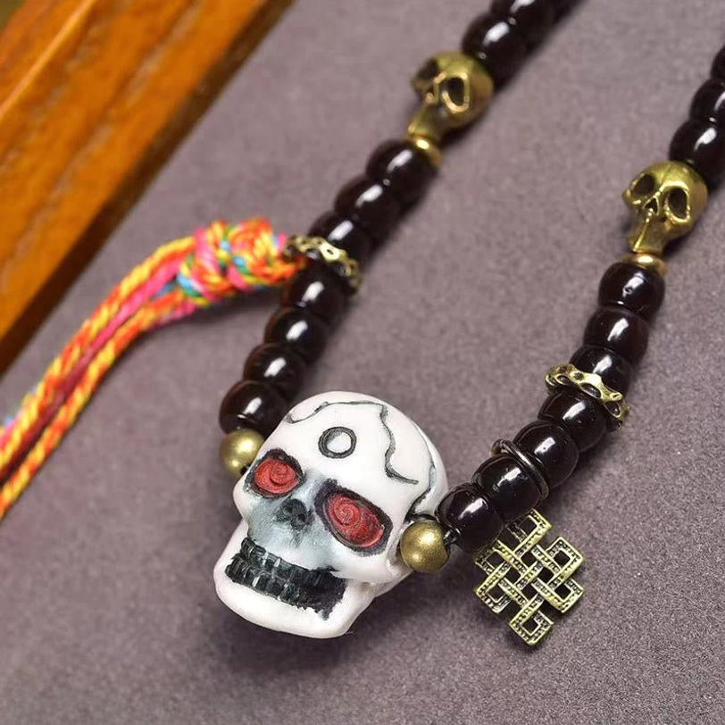 Detailed view of brass skull spacer beads and carved eternal knot charm on Tibetan bracelet
