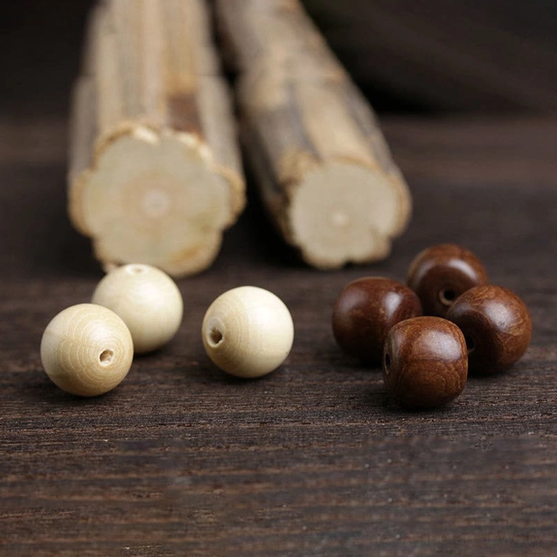 Unstrung Abelia Biflora wooden beads and Hetian jade components arranged on dark wooden surface