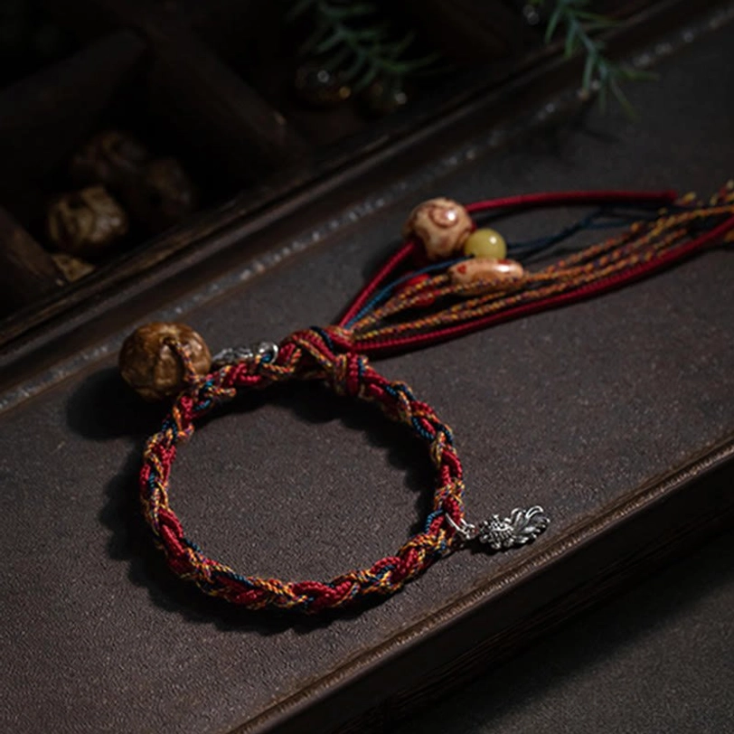 Tibetan red string bracelet with silver ruyi charm and natural wooden beads loose components on dark surface