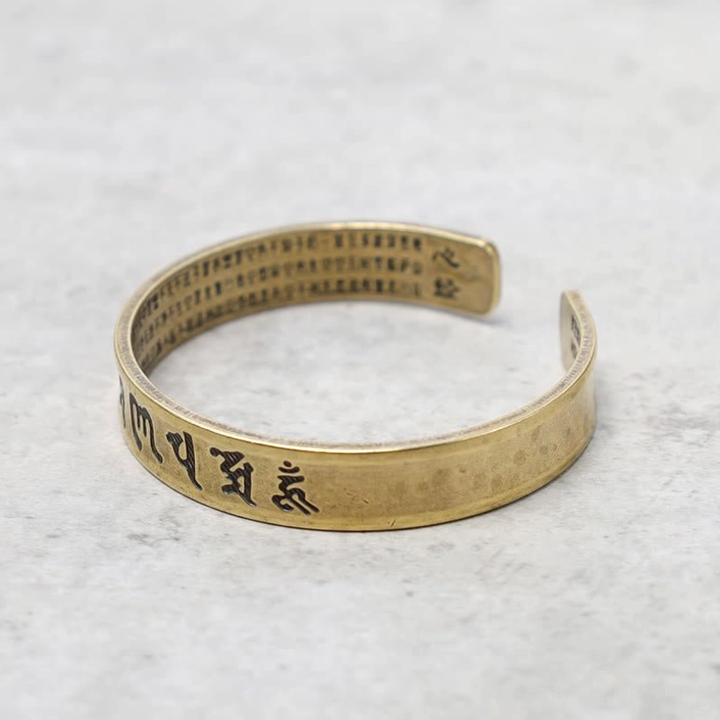 Double-sided engraved Tibetan mantra bracelet showing outer six-word mantra and inner sutra