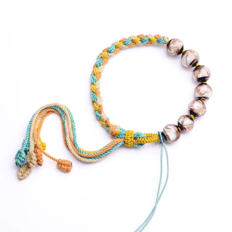 Complete Tibetan multicolor rope liuli glass bracelet displayed on pure white background, minimalist clean product shot showing adjustable cord ends