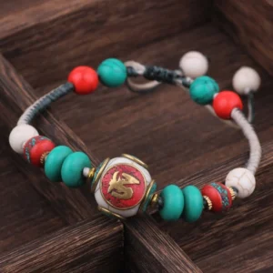 Flat turquoise black white braided rope Tibetan bracelet with script center bead on wooden surface