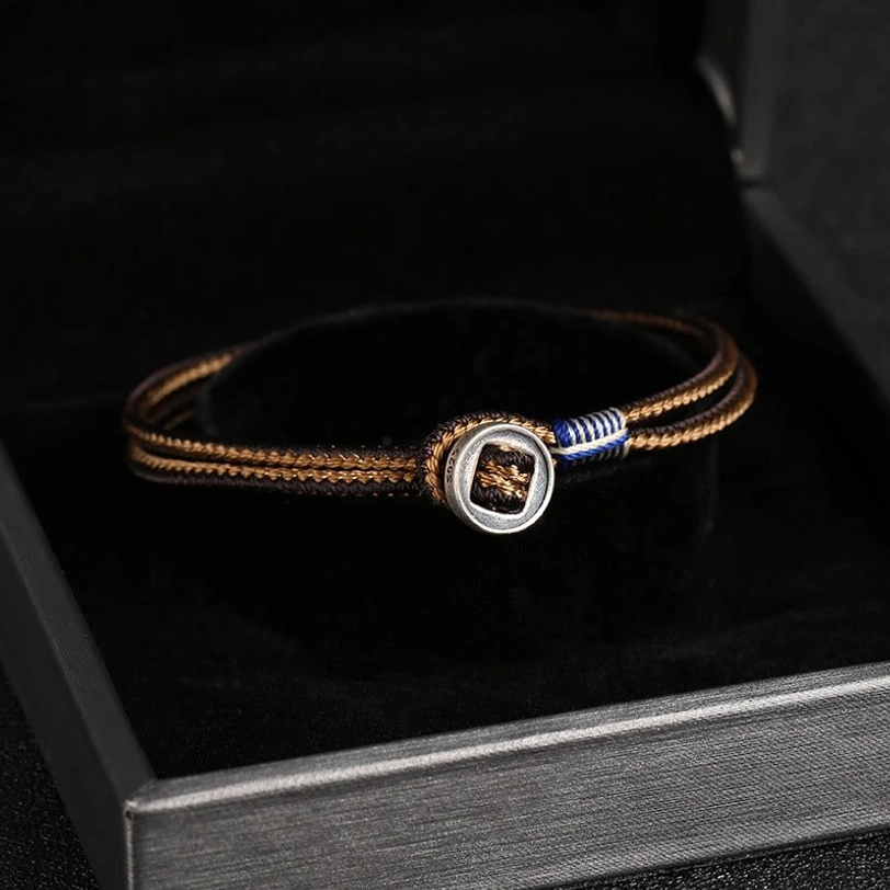 Tibetan silver protection bracelet with brown and blue woven cord inside open silver jewelry box, detailed clasp view