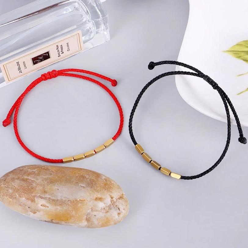 Red and black Tibetan copper bead bracelets styled with stone and perfume bottle, spiritual lifestyle photography