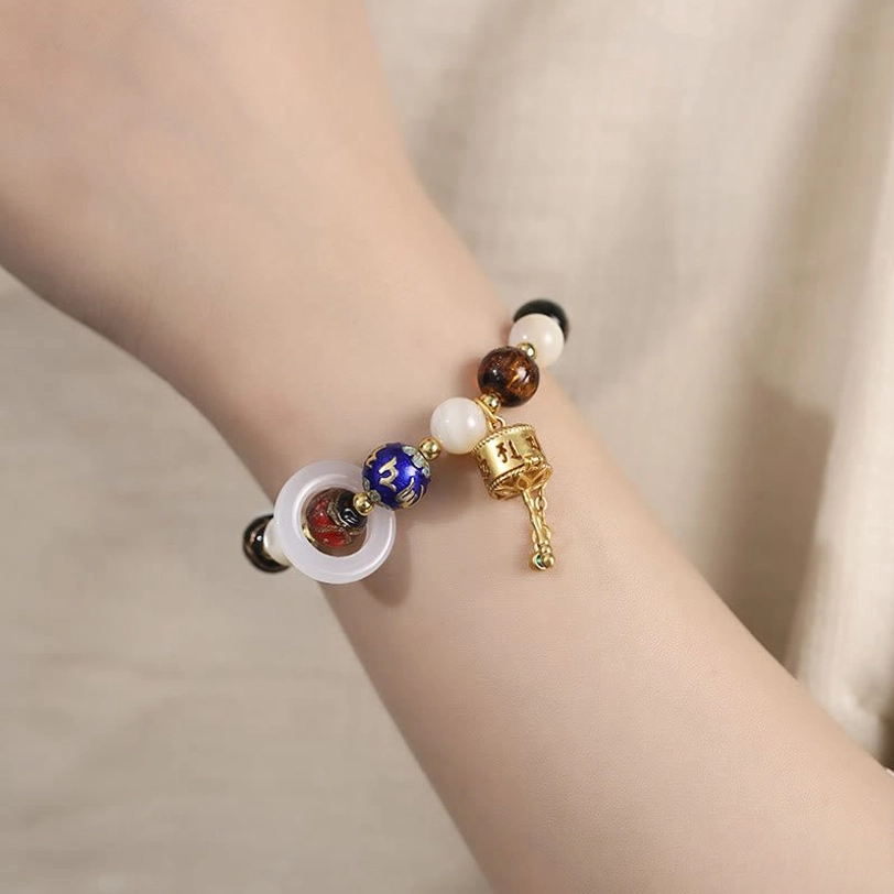 Tibetan prayer wheel bracelet worn on wrist showing mixed gemstone beads and gold metal pendant