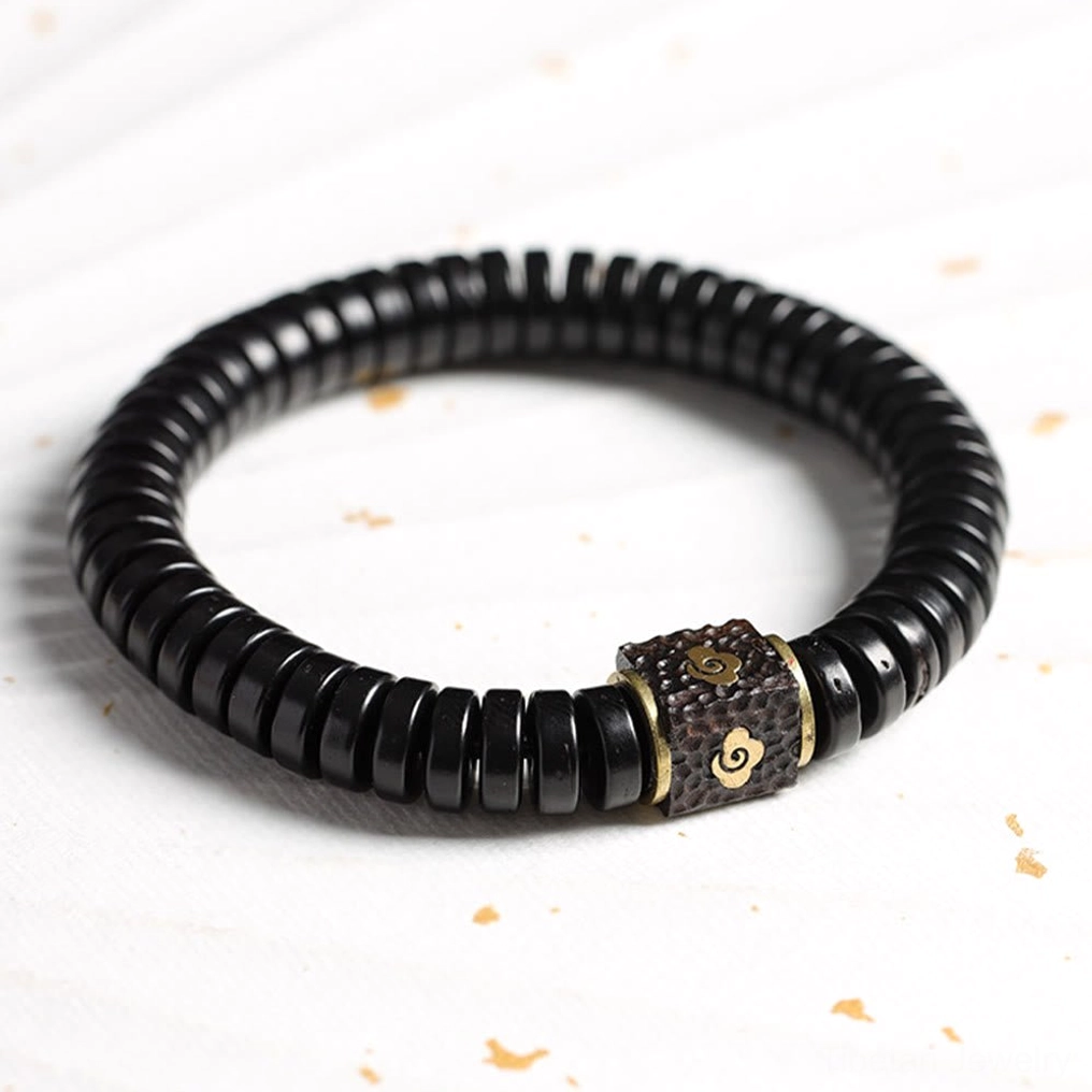 Coconut shell auspicious bracelet overhead flat lay with neatly arranged black beads and detailed metal accent