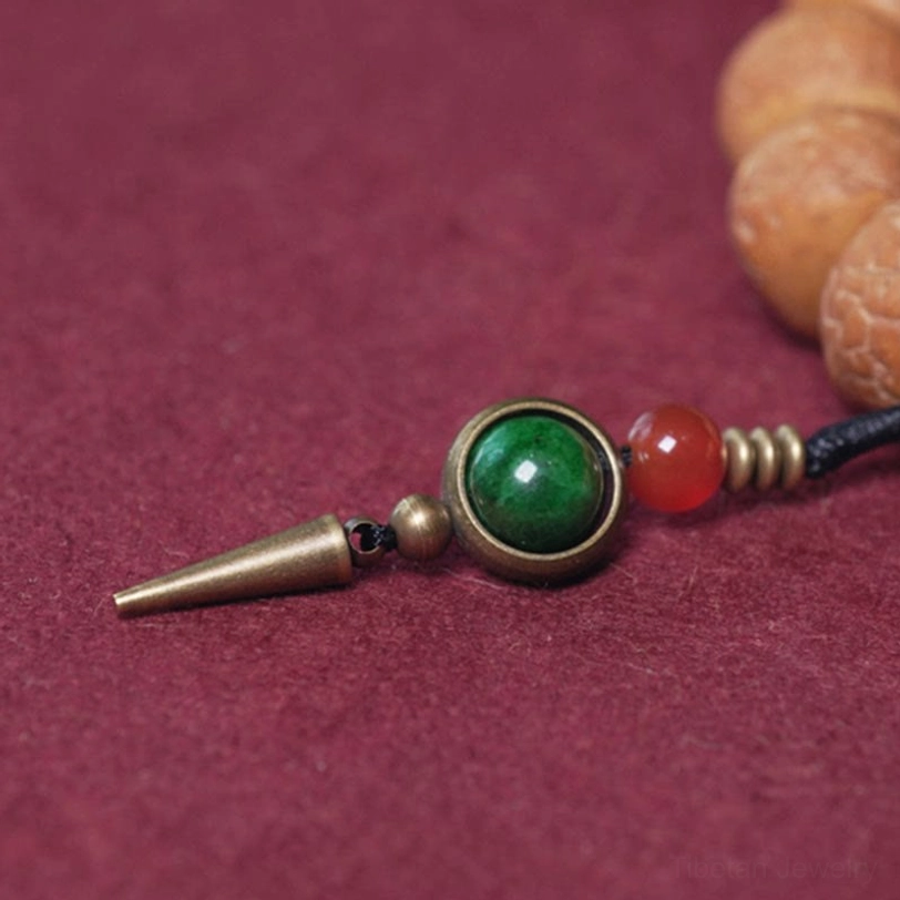 Tibetan bracelet pendant charm featuring green jade bead, red agate bead, and brass cone accessory