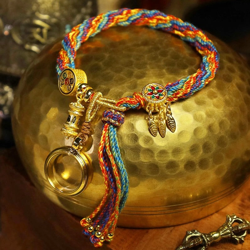 Sacred Tibetan woven bracelet with prayer wheel charm and multicolor twisted rope displayed by singing bowl