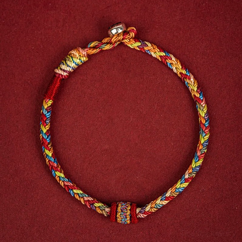 Top-down view of handcrafted Tibetan multicolor braided blessing bracelet with central decorative knot and metal clasp