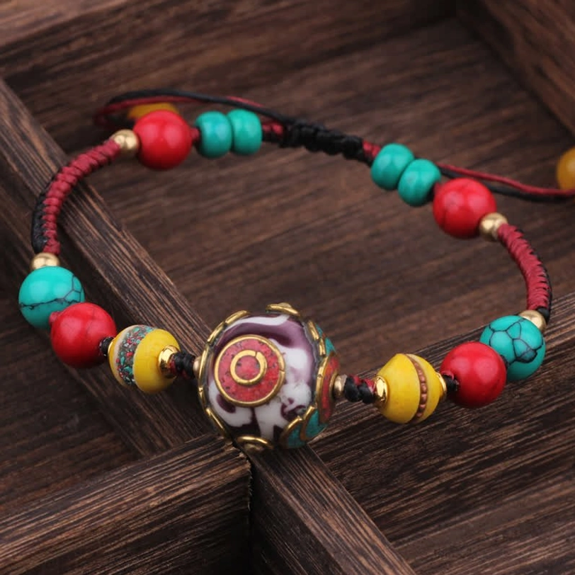 Red yellow turquoise Tibetan beaded bracelet with ornate enamel center bead flat lay