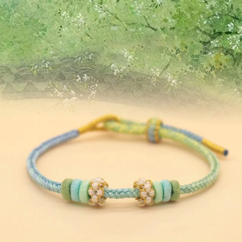 Mint blue pastel eight-thread braided bracelet with floral beads on green ancient garden background