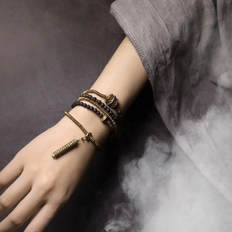 Tibetan lava stone beaded bracelets stacked on wrist side view with dangling tassel charm